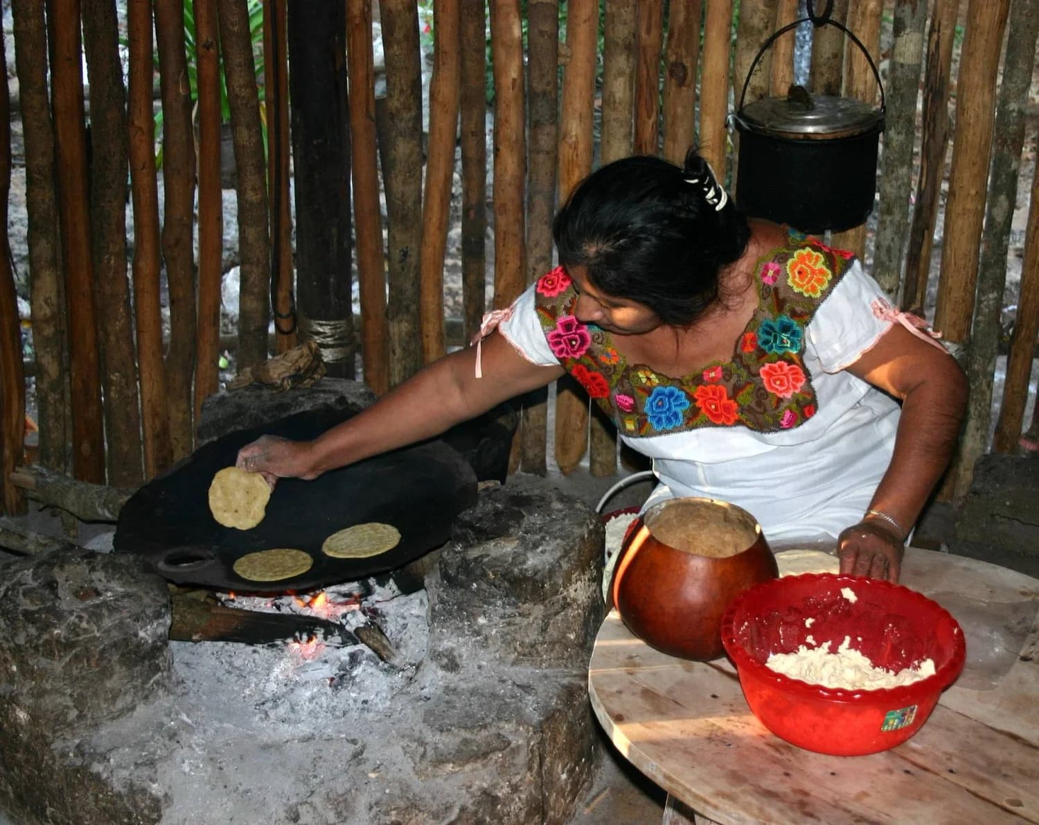 Cocinera volteando tortillas sobre el comal