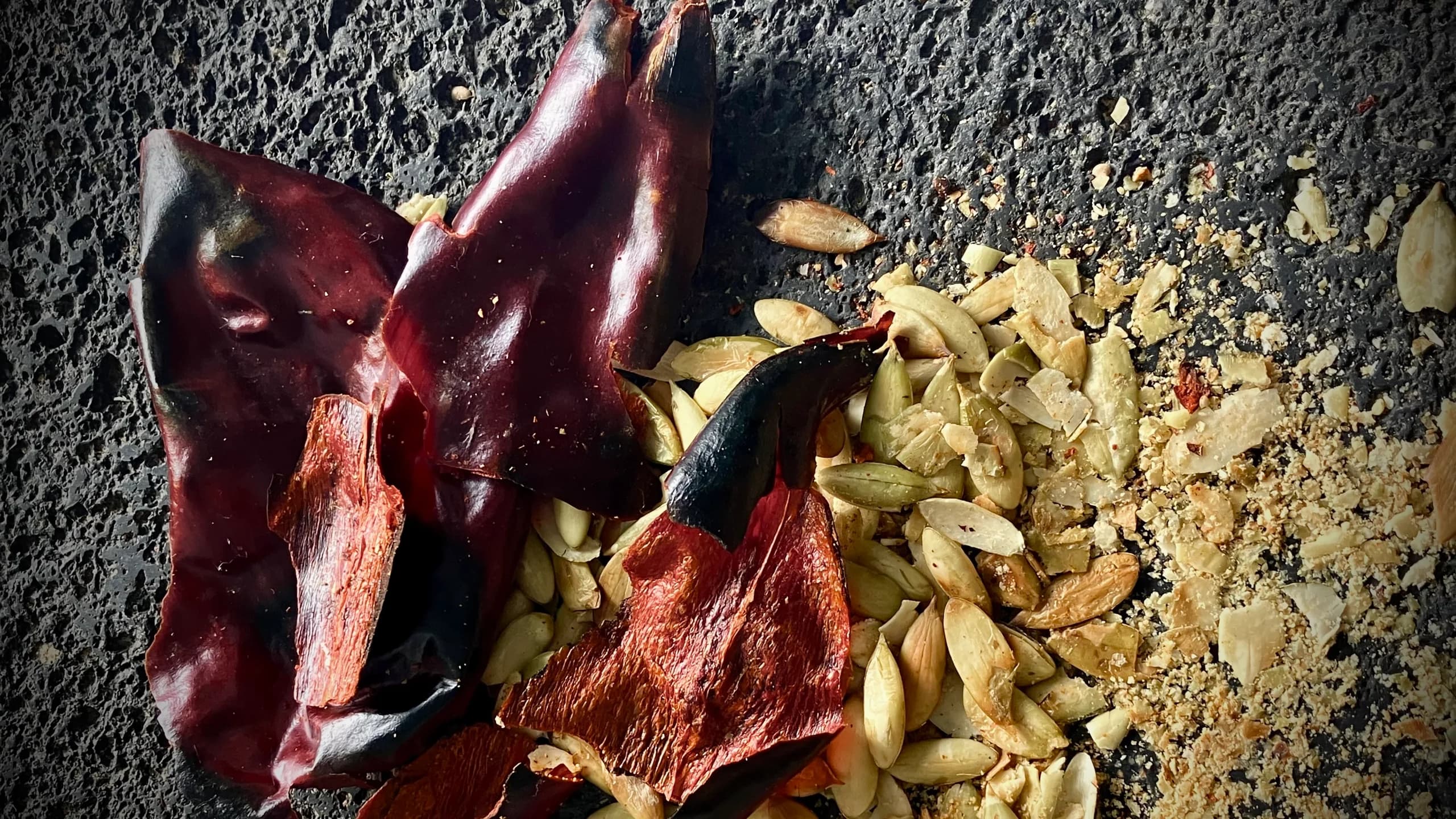 Chiles and pumpkin seeds on a metate