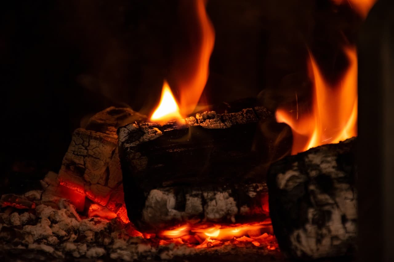 Cuts of meat grilling over embers and flames in an ancient brick kitchen