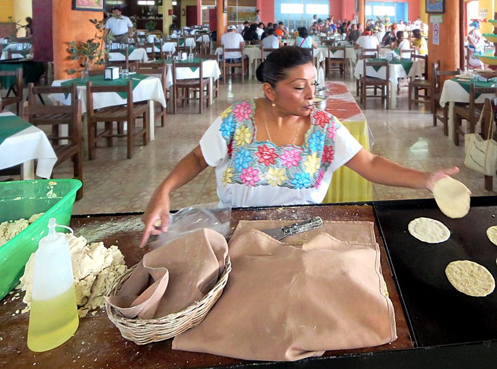 Manos de mujer dando forma a una tortilla de masa de maíz